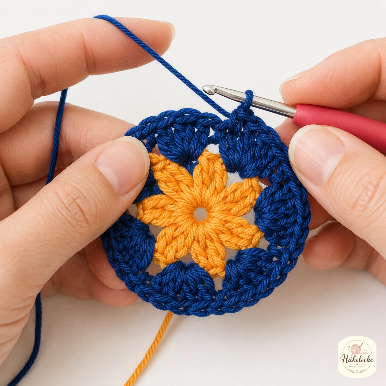 In Runde zwei umschließt Navy die orangen Blütenblätter der African Flower Granny Square Anleitung