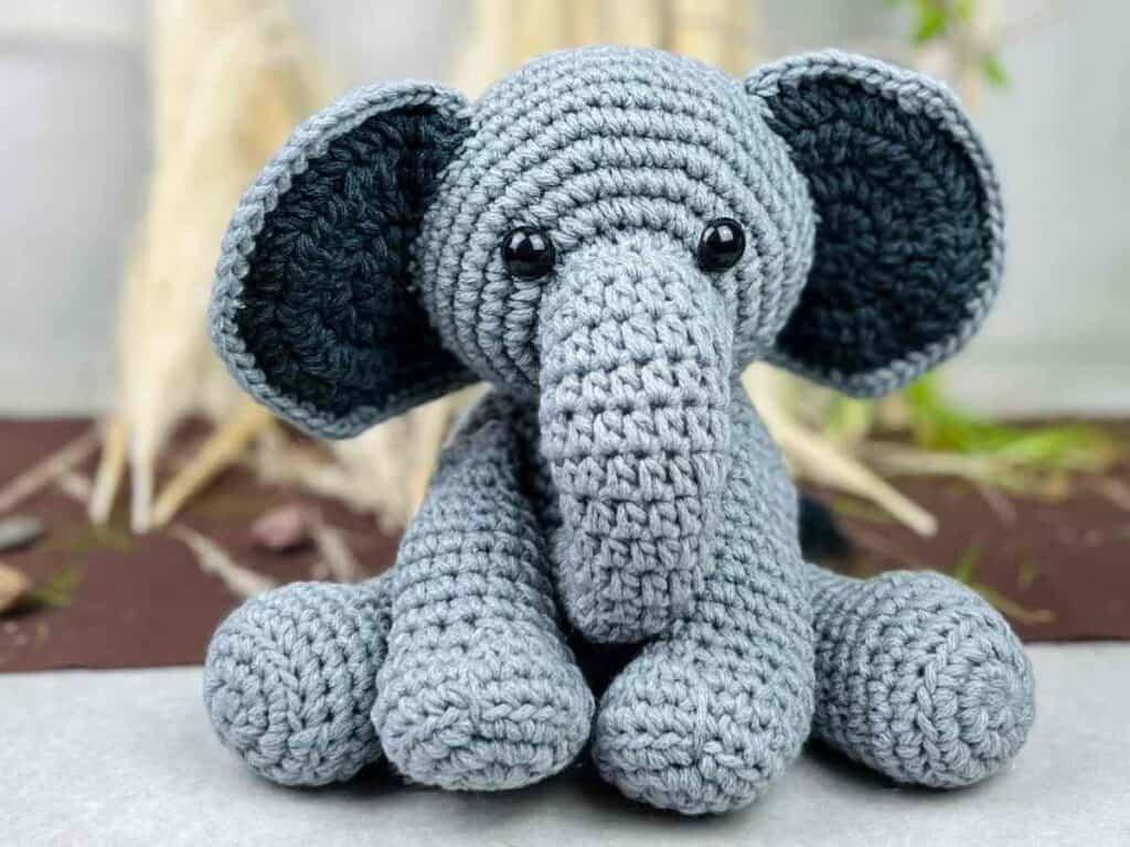 Grauer Amigurumi-Elefant mit großen rosa Ohren und Rüssel