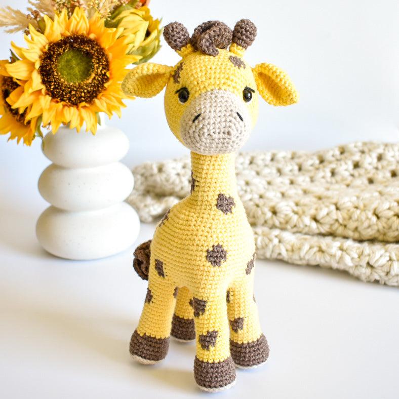 Gelbe Amigurumi-Giraffe mit braunen Flecken und kleinen Hörnchen