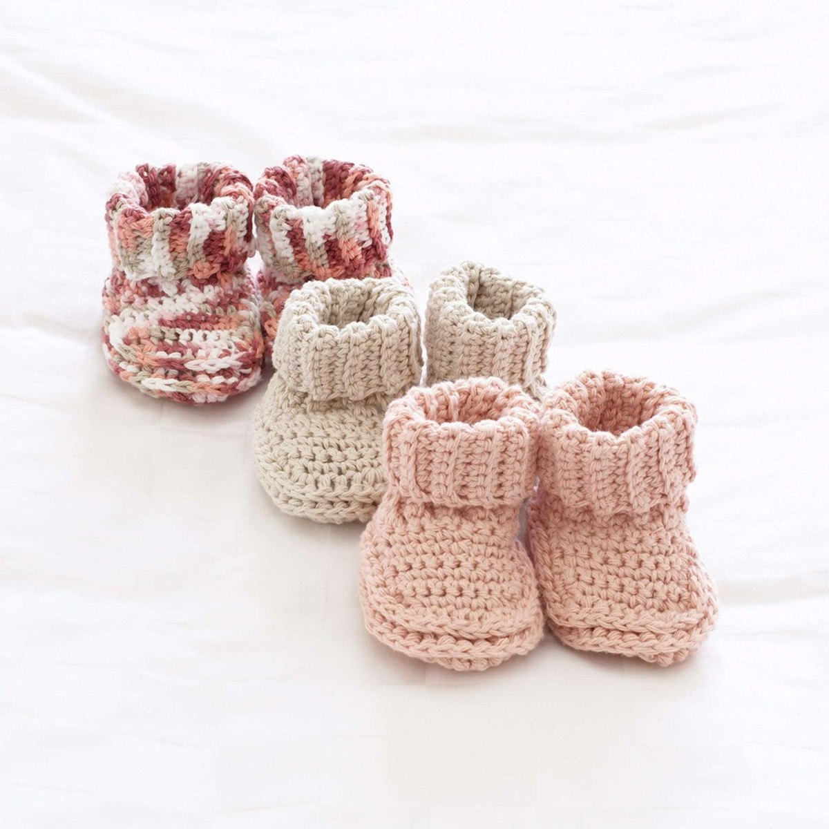 Drei Paar gehäkelte Babyschuhe in unterschiedlichen Größen