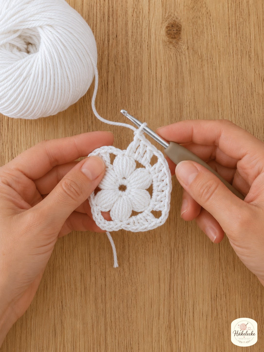 Zweite Runde mit ersten Ecken entsteht beim Blumen Granny Square weiß häkeln um die Blüte.