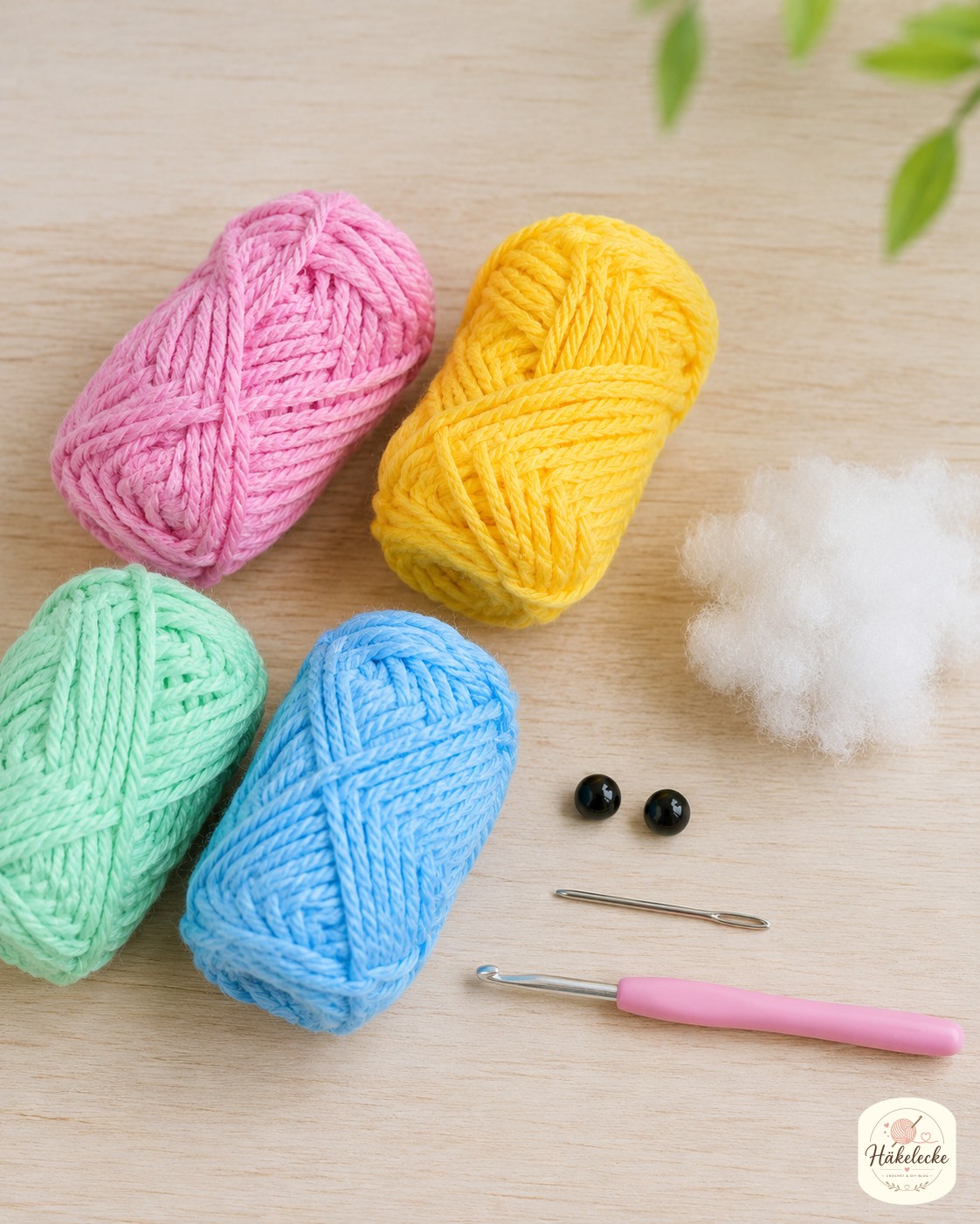 Buntes Garn in Rosa, Gelb, Mint und Blau liegt bereit, um eine bunte Schnecke Amigurumi zu häkeln.