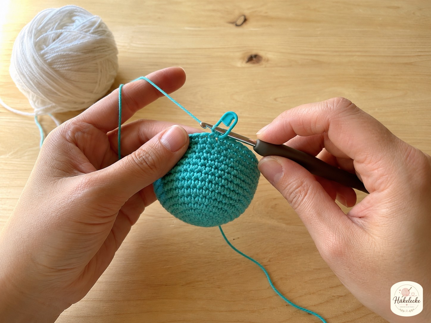 Größere türkise Amigurumi-Kugel mit gesetztem Maschenmarkierer