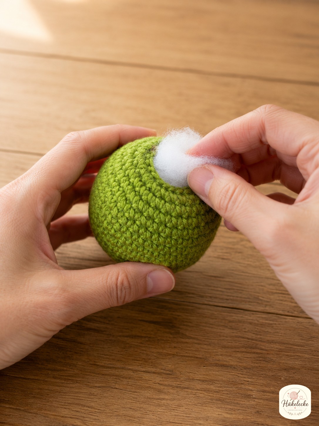 Fertige grüne Kopfkugel wird mit weißer Füllwatte gestopft beim Grinch Amigurumi mit Schal häkeln