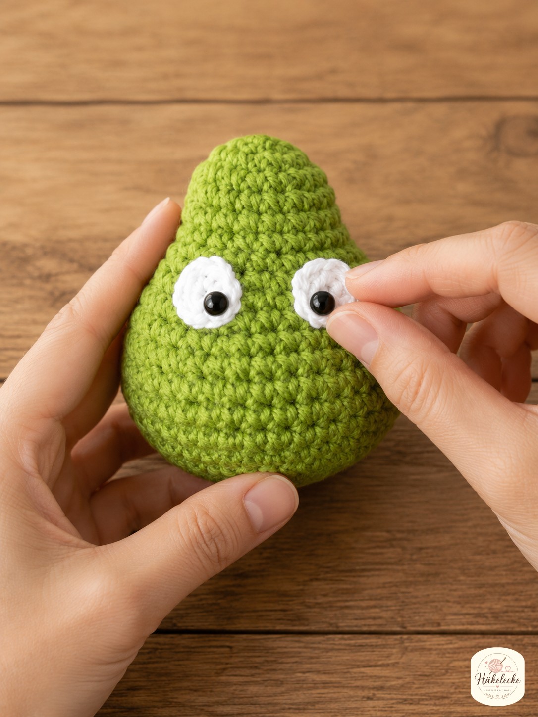 Sicherheitsaugen werden in den grünen Amigurumikopf gesteckt, das Gesicht des Grinch nimmt Form an