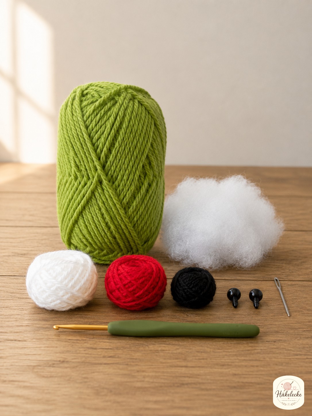 Grüne, weiße, rote und schwarze Wolle mit Häkelnadel als Material zum Grinch Amigurumi mit Schal häkeln bereitgelegt