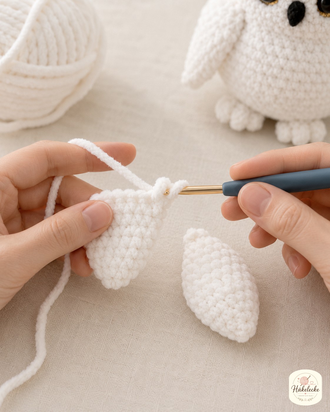 Zwei tropfenförmige Flügel entstehen beim Schneeeule Amigurumi häkeln, einer fertig, einer auf der Nadel