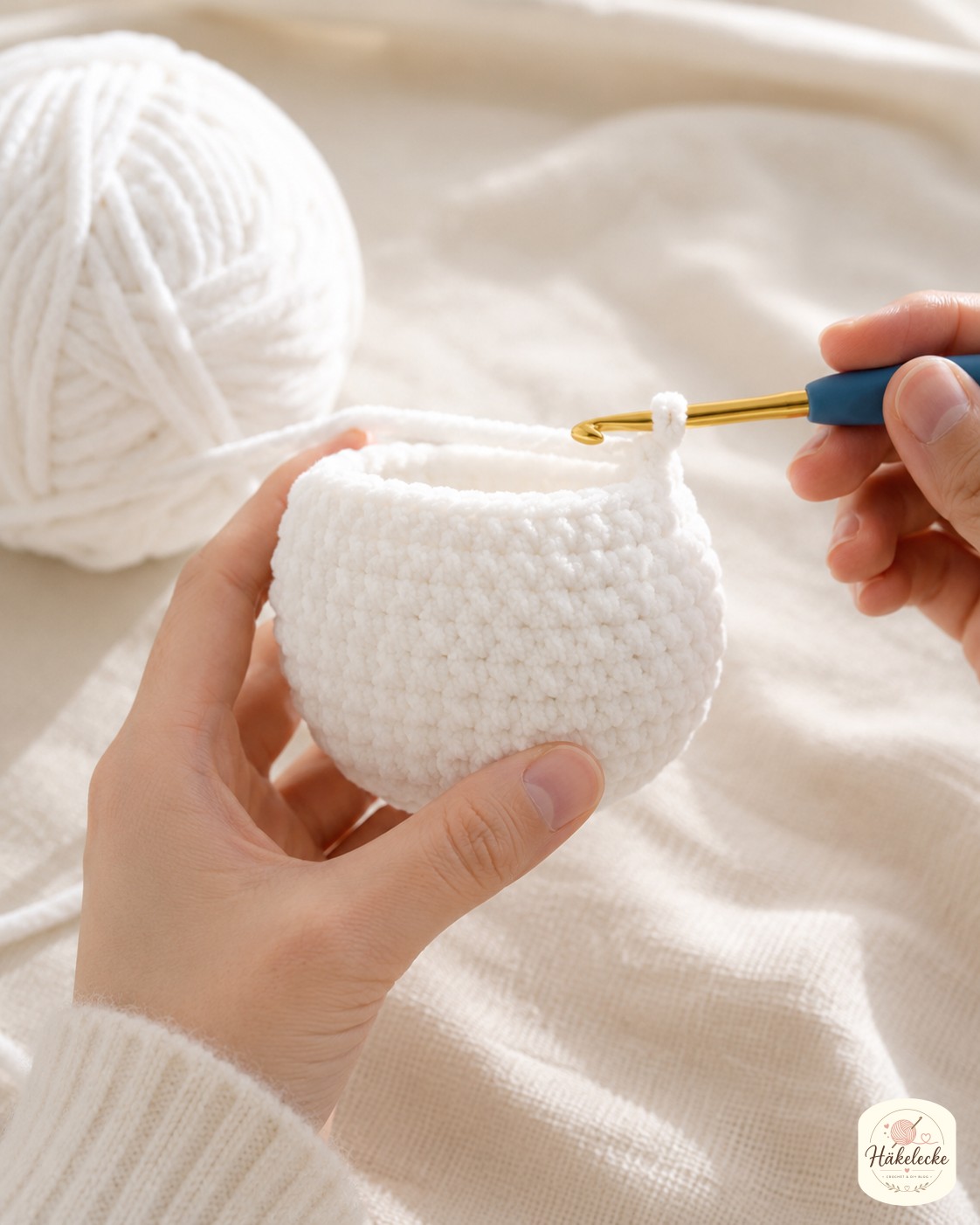 Hände häkeln den Kopf für die Schneeeule Amigurumi in weißem Chenille-Garn mit sichtbaren Zunahmerunden